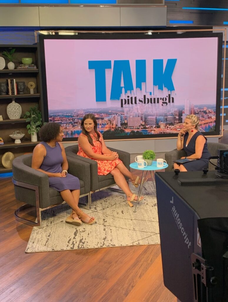 Three women sit on couches in a television studio for Talk Pittsburgh.