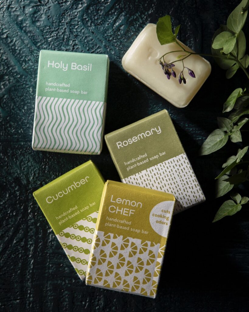 Four boxes of soap sit beside a bare bar of white soap.