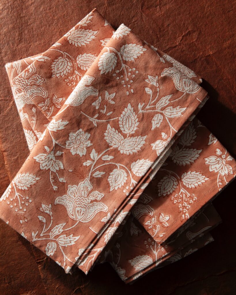 Two orange printed napkins folded on an orange table.