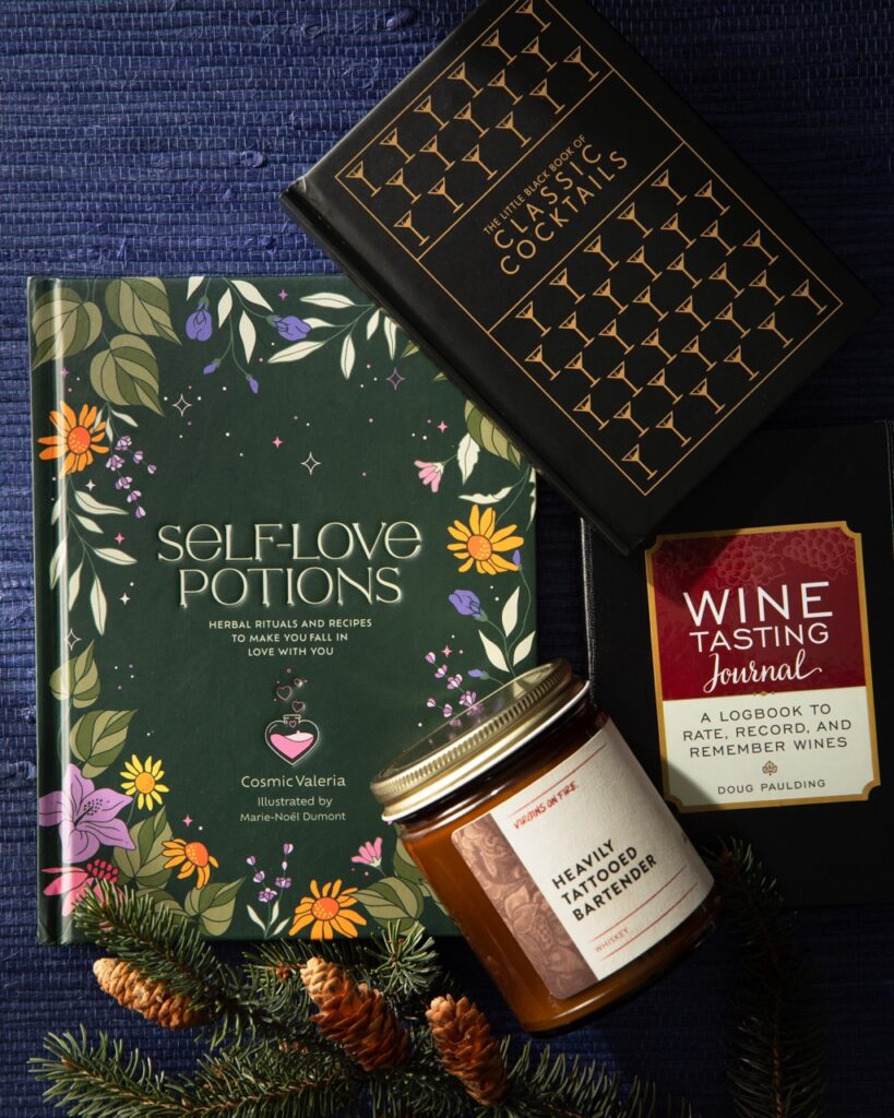 Three small books and a candle sitting on a blue table.