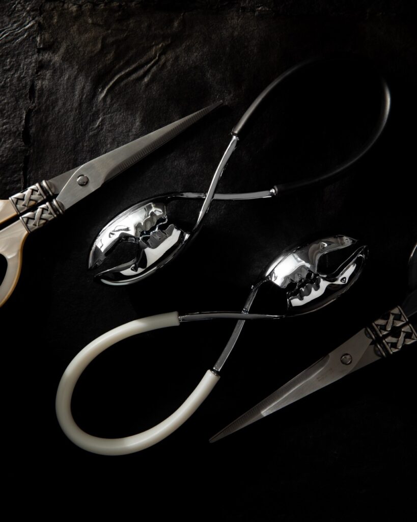 Two salad tongs sit between two pairs of kitchen scissors.