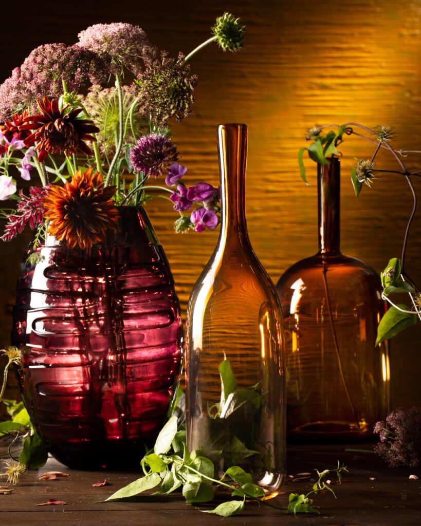 Three vases made our of recycled bottles with flowers in them.