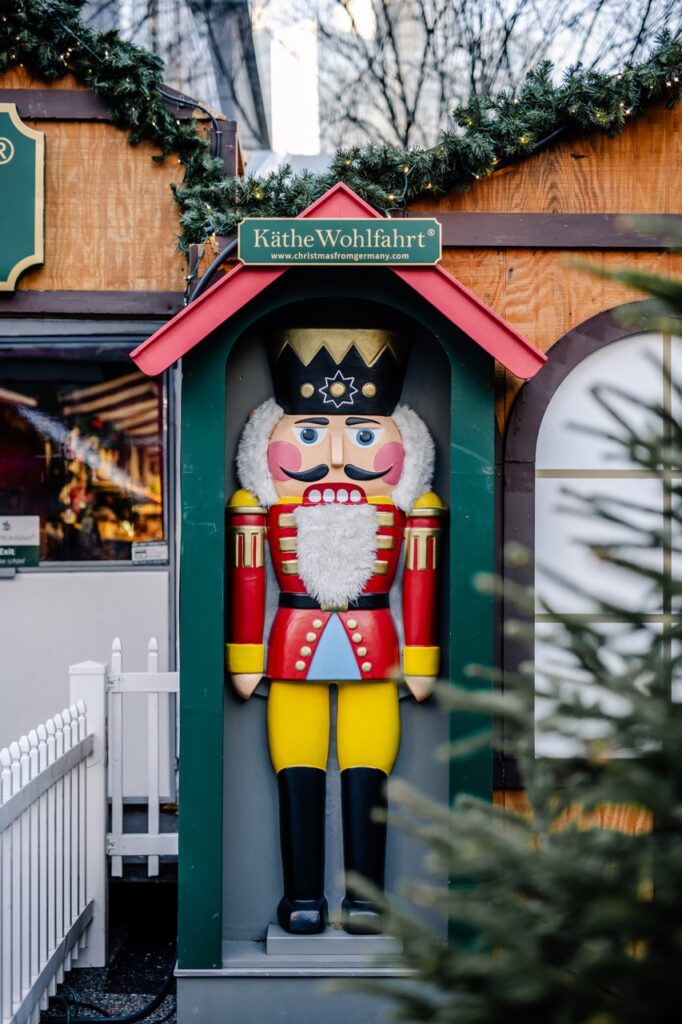 A tall nutcracker statue stands in a small hut outside.