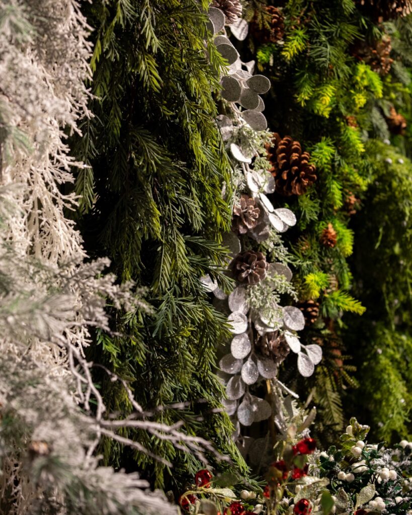 Various strings of pine hang in green and white colors with pinecones throughout.