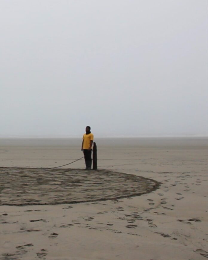 In a land-based work by Eugene Macki, a man stands in a foggy, grey desert plain