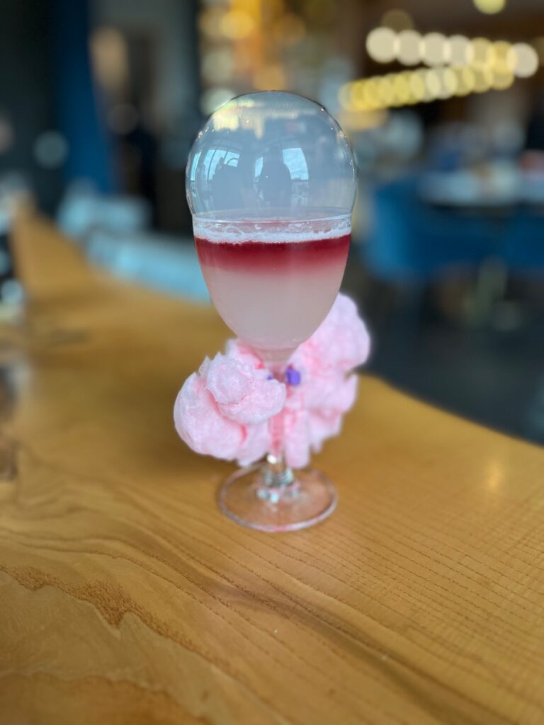 A pink cocktail in a large glass on a counter at Spirits & Tales