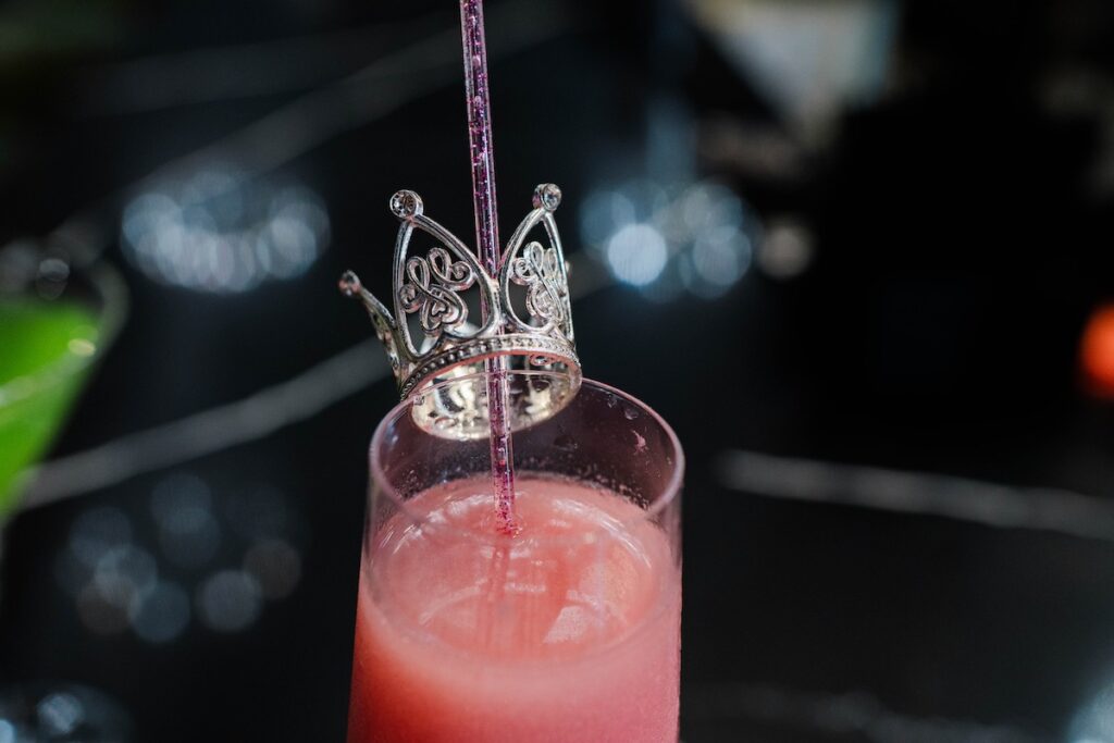 A pink cocktail with a crown in it, meant to look like Glinda from Wicked