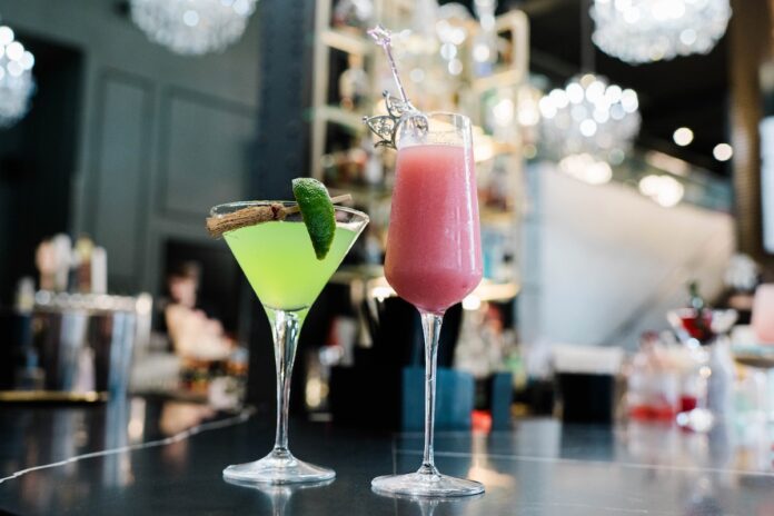 A green cocktail and a pink cocktail celebrating Glinda and Elphaba from Wicked on a counter at Pittsburgh restaurant Ritual House