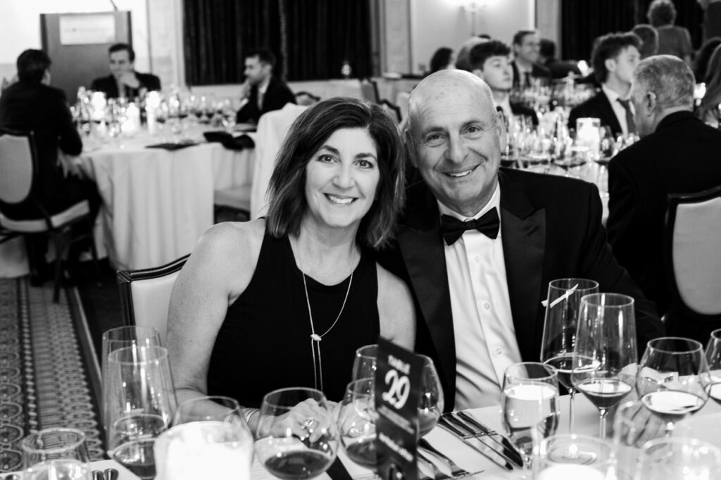 A black and white photo of a man with a jacket and bowtie next to a woman in a tank top style dress.