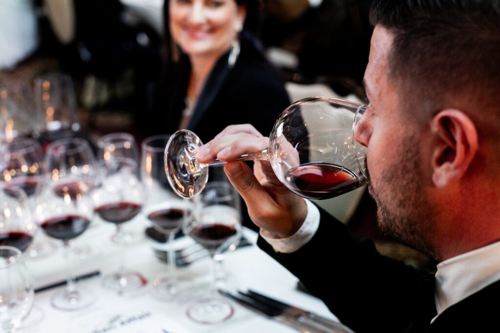 A man tastes a small sample of wine from a wine glass.