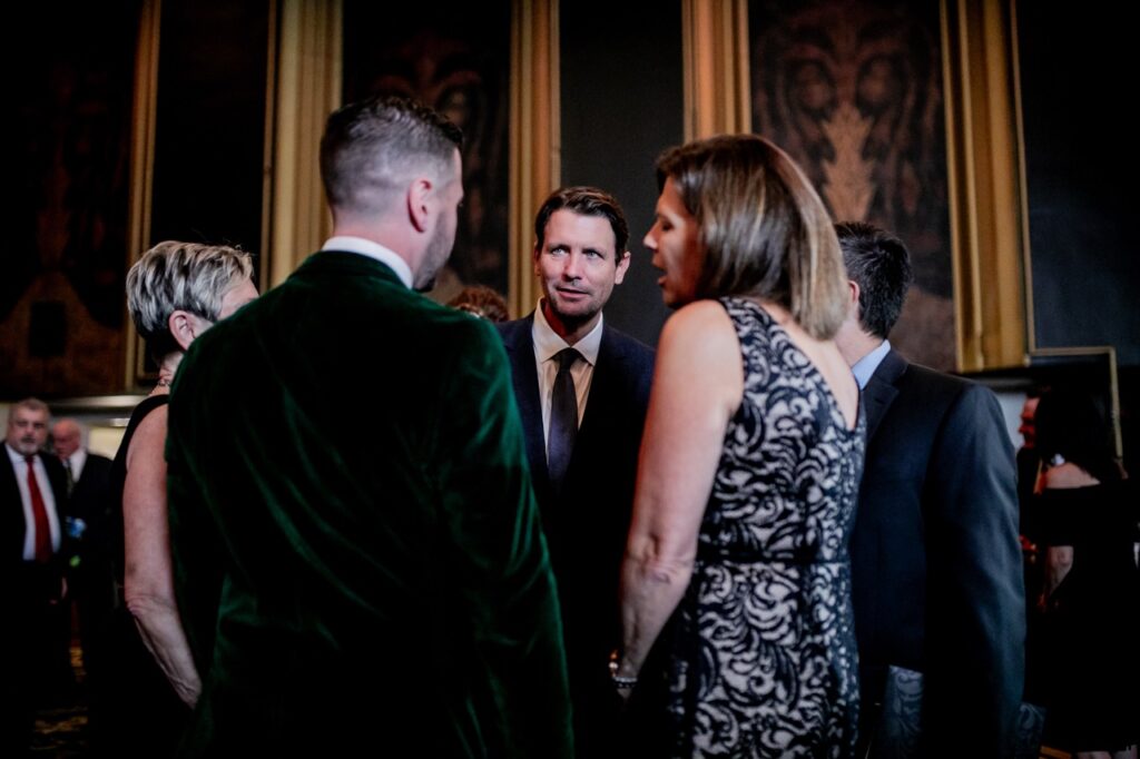 A group of three men and two women speak to each other.