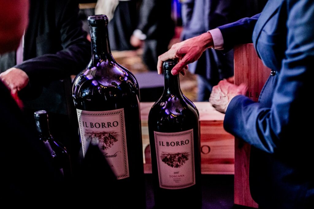 Two large bottles of Il Borro wine sit next to each other as a man in a black suit handles one.