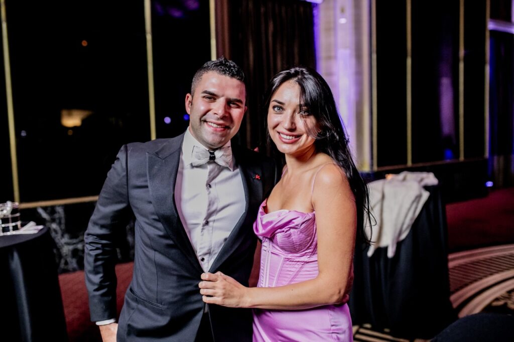 A woman in a pink dress grabs onto the suit jacket of a man.