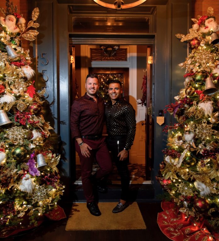 Justin Matase and Dr. Elie Aoun pose in front of their festively decorated home.