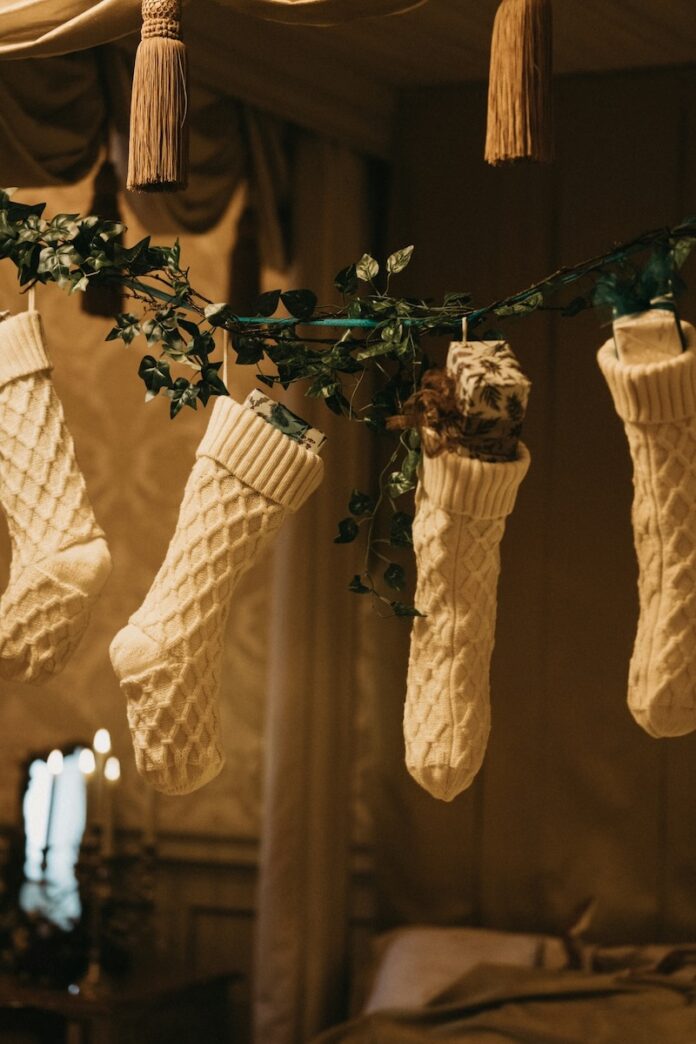 Four white stockings hang from a rope, each stuffed with wrapped presents.