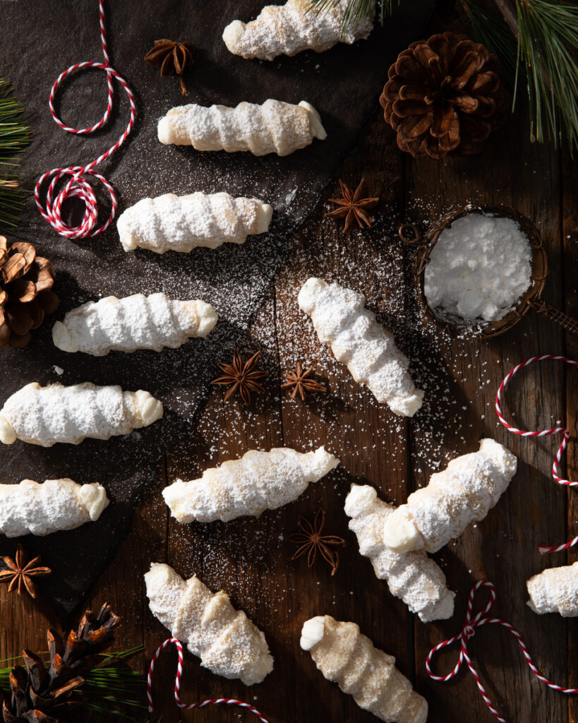 Small white cookies, lady locks, on a dark brown background