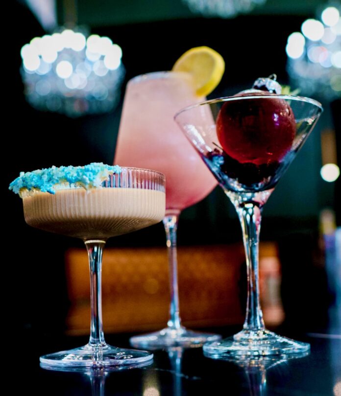 Three winter cocktails from Ritual House sit on a black bar