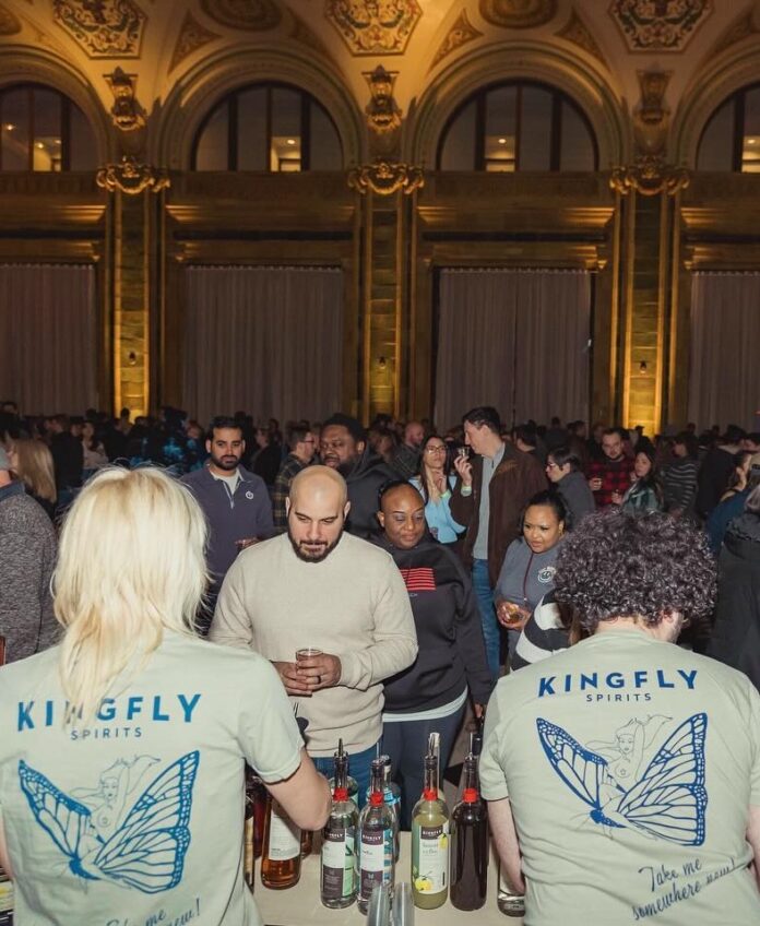 Two people in Kingfly shirts serve cocktails to patrons at a Pittsburgh Spirits event in February.