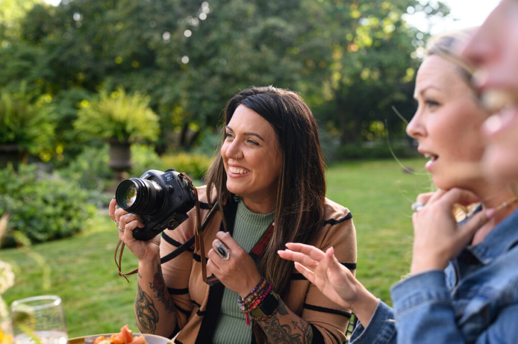 A woman with a camera, seemingly in the midst of capturing a moment at the outdoor gathering.