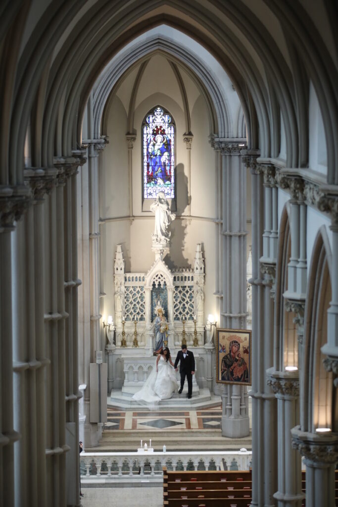 The bride and groom standing together in a grand, ornate cathedral.