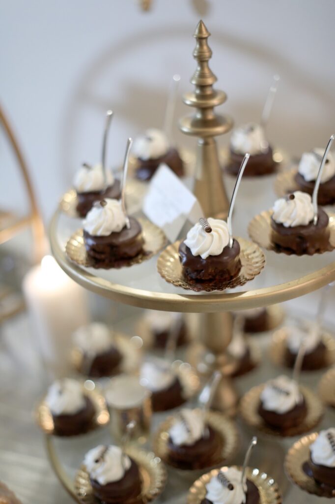 Small cupcake bites with frosting on top sit on a gold stand.