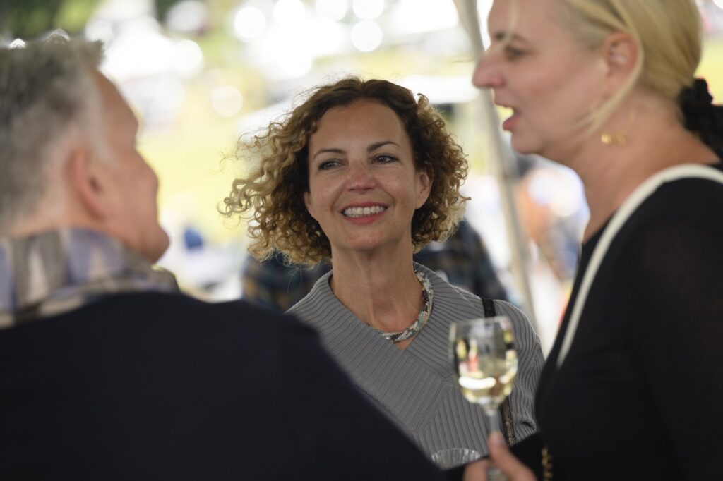 A woman with curly blonde hair smiles at a man in a black sweater and scarf.