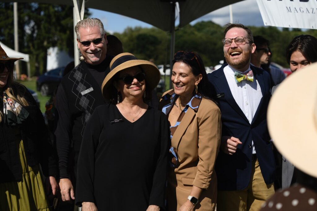 Two men and two women laugh as they pose for a photo outside of a white tent.