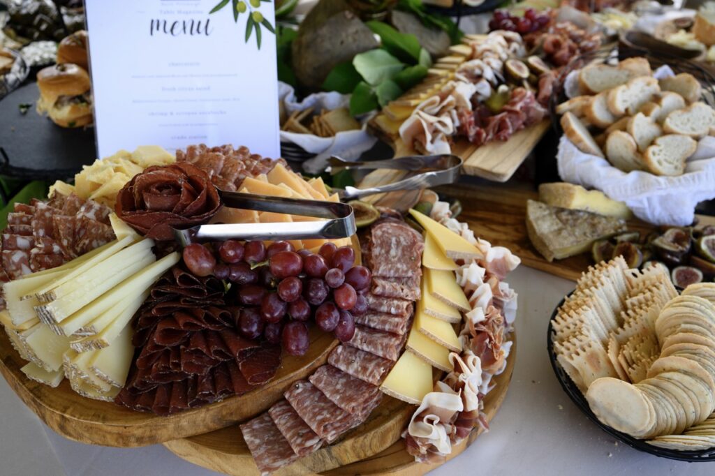 A large charcuterie spread with meats, grapes, crackers, slices of bread, and cheese.