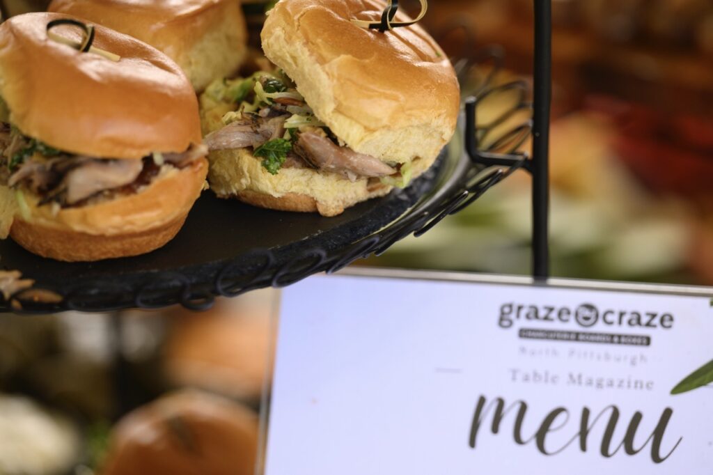 Various small sliders sit on a black tray above a Graze Craze menu.