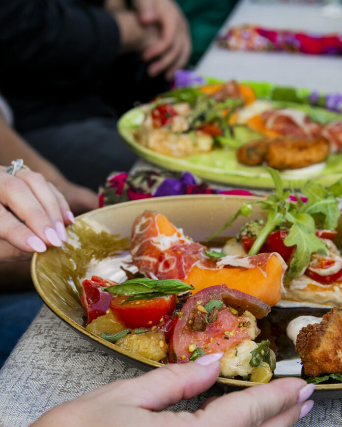 Garden Party Goodness A vibrant and colorful salad plate, filled with a variety of fresh, garden-fresh ingredients. The hands of the person enjoying this "garden party goodness" can be seen in the frame, further emphasizing the fresh, homemade nature of the dish.