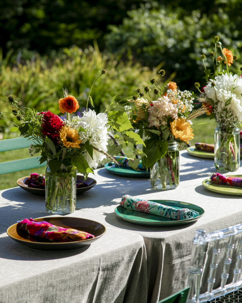 A beautifully arranged outdoor dining table set in a lush, green garden setting.