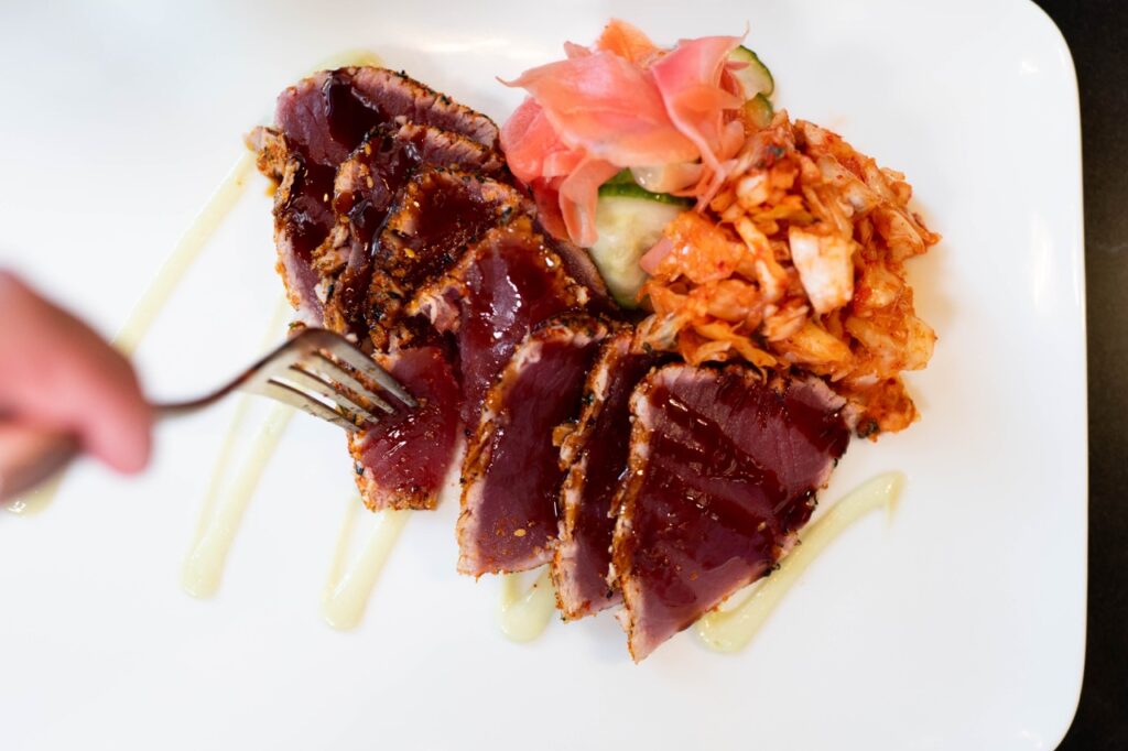 A white plate with tuna stacked on it.