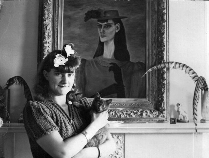 Painter Gertrude Abercrombie besides "Self Portrait with My Sister," holding her black cat.