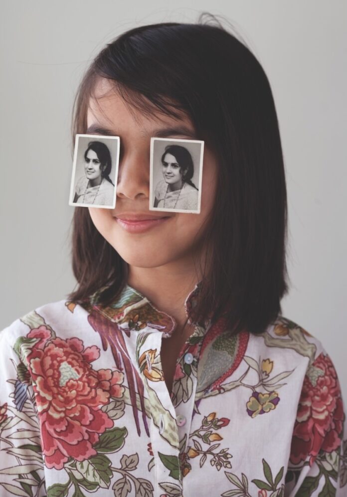 A photography work by Priya Suresh Kambli showing a figure with two black and white photographs over their eyes.