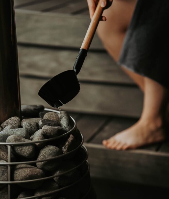 A figure pours steam on hot stones in Signal Sauna