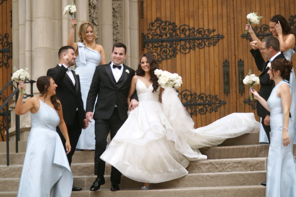 The bride and groom, along with their wedding party, posing on the steps outside the cathedral after the ceremony.