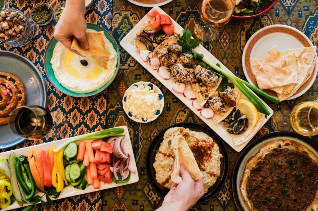Various platters sit on a pattern table as people reach for food.