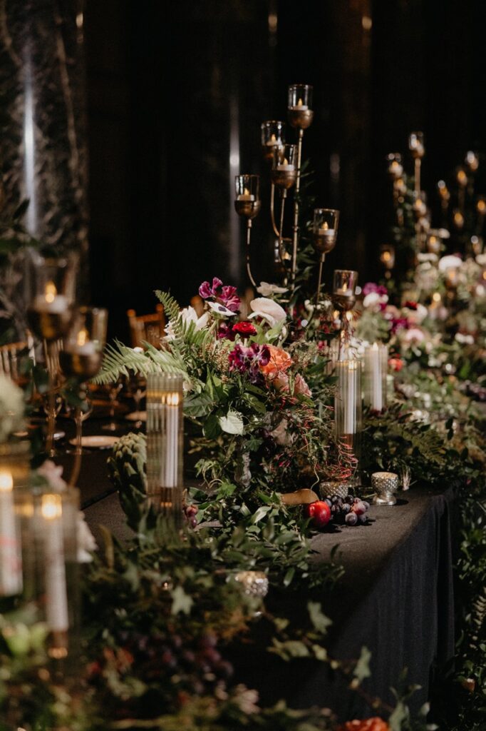 Plenty of flowers and greenery and candles sit amongst the wedding party table.