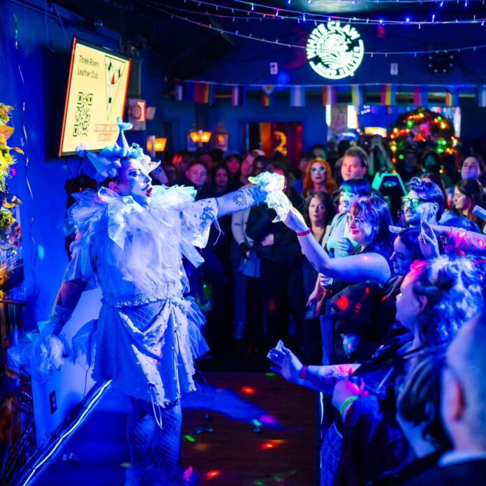 The Pittsburgh Drag Community Only Strengthens in Times of Crisis A drag performer in Pittsburgh dances on stage, taking a dollar bill from a person standing off stage in the audience.