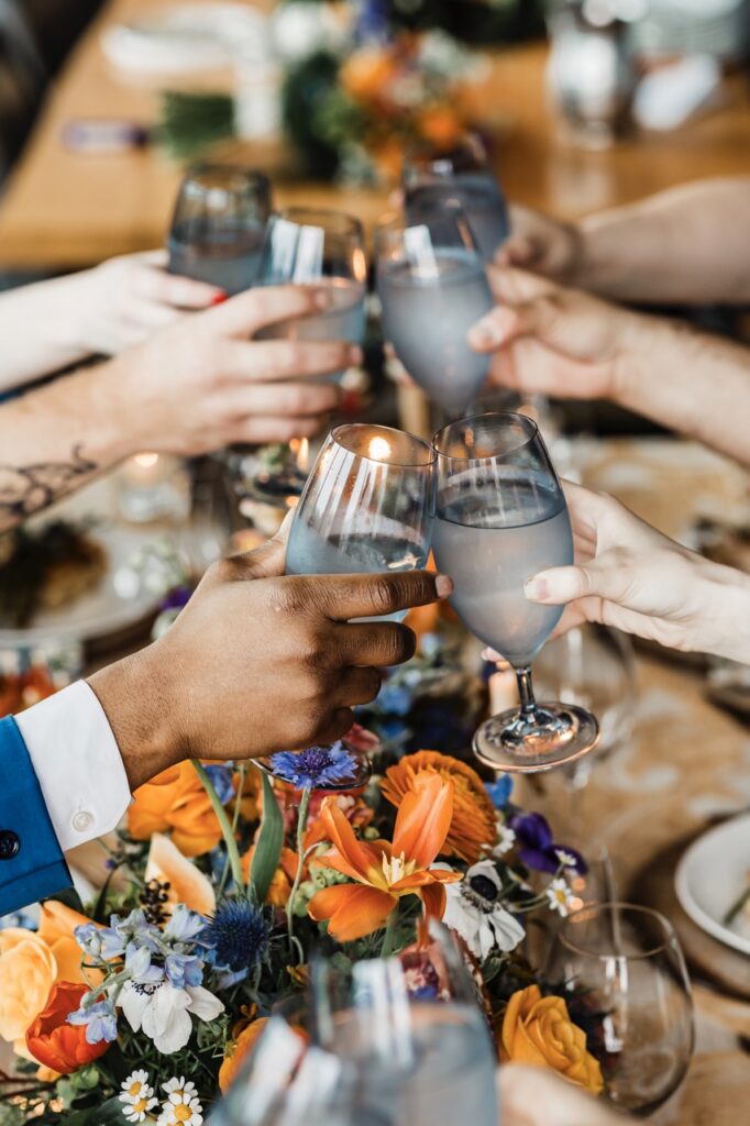 A group of guests at a wedding clink cocktail glasses supplied by a wedding service.