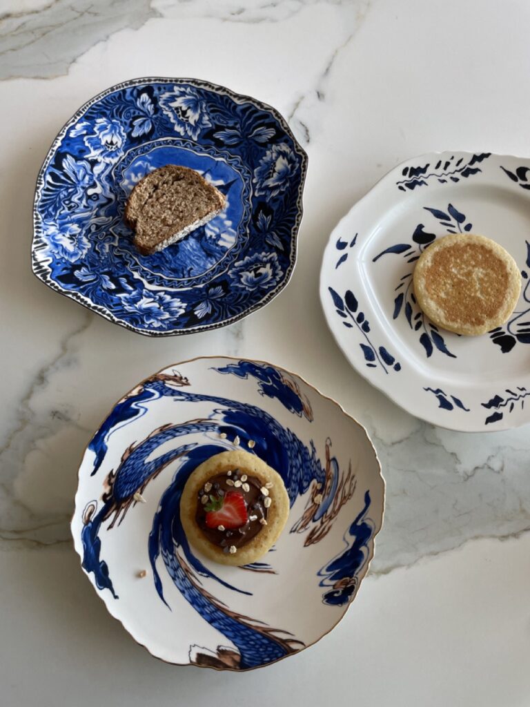 Three bowl-like plates in blue and white delftware sits on a marble table.