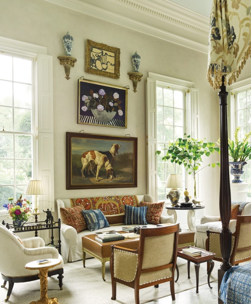 A living are decorated with paintings, big windows, and green plants throughout.