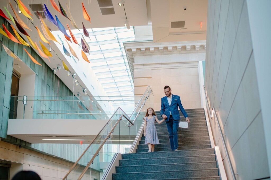 A father and daughter walk down the stairs at Columbus Museum of Art.