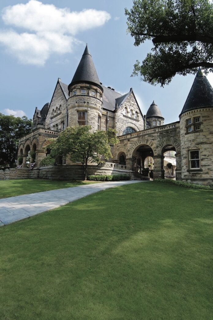 The outside of Buhl Mansion in Pittsburgh with a green grass field in front of it.