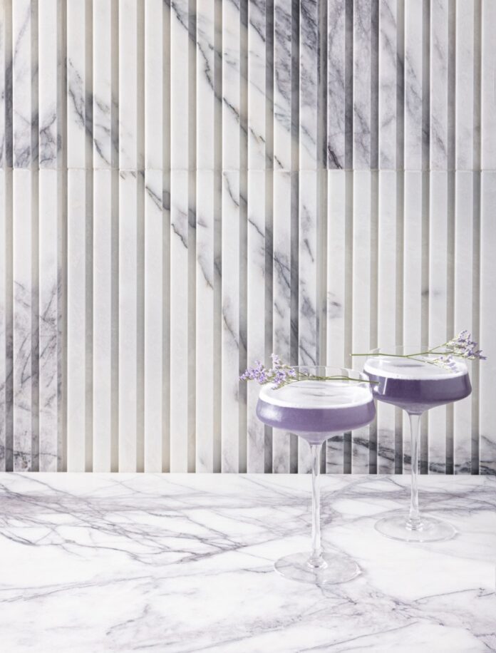 Surrealism Tops Spring 2025 Fashion and Home Trends Two tall glasses hold surrealism purple cocktails against a lavender and white wallpaper.