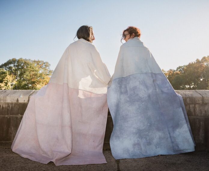 Two women in textile shawls by Leah Patgorski.