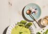 Chilled Pea Soup with Mint A white bowl holds a Chilled Pea Soup with radish and mint garnishes as a bowl of peas sits off to the right.