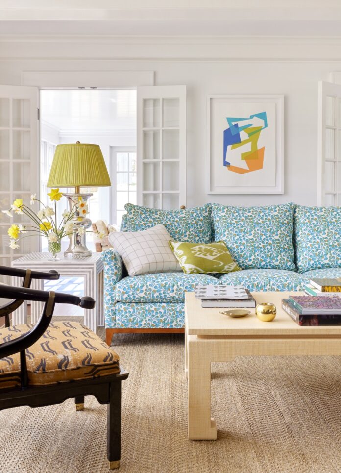 Colleen Simonds Updates a Charming New Jersey Farmhouse A light blue patterned couch with a green pillow on it and a green lamp to the left sitting in a living room.