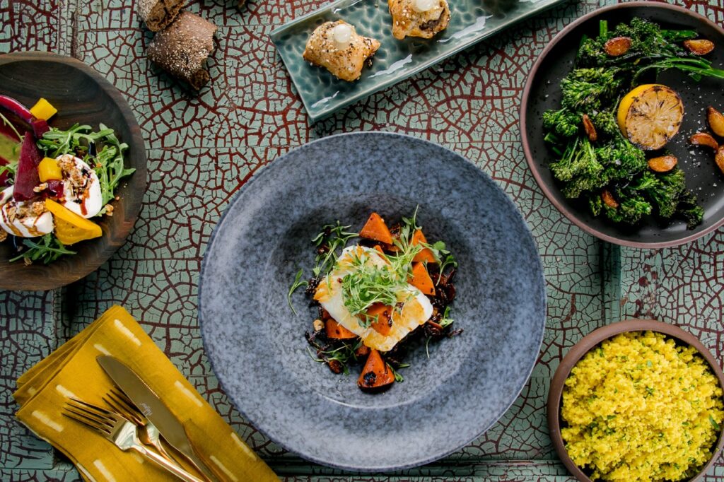 A large blue plate with a fish entree sits surrounded by other small plates from Common Plea Catering.