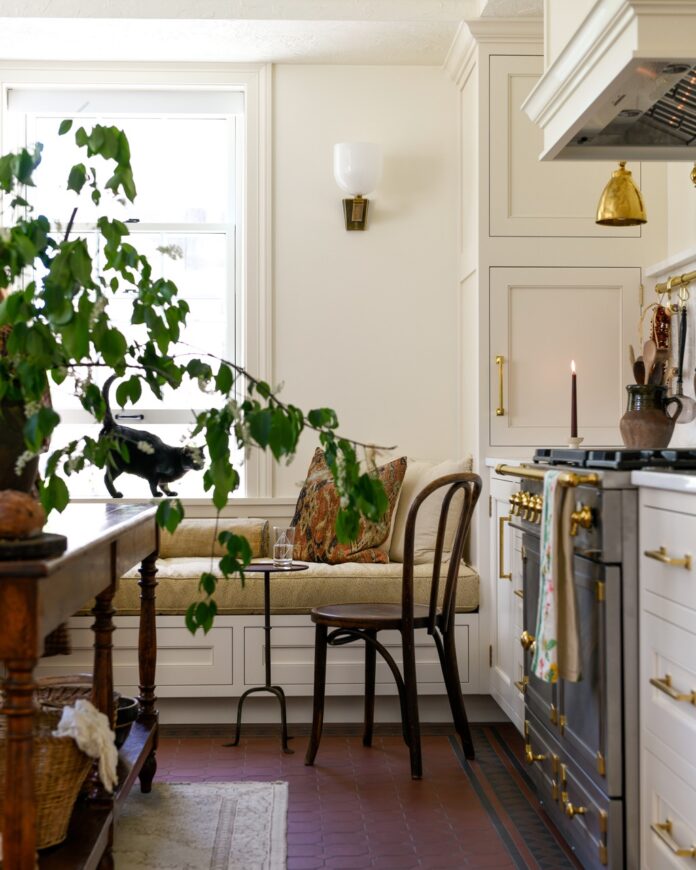 Cruze Architects and Drury Cabinetry Collaborate on a New Kitchen Part of a Cruze Architects designed kitchen with a nook reading area, plants on the dining table, and a metallic stove between white counters.